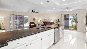 A modern kitchen with white cabinets, a black countertop, and a built-in dishwasher.