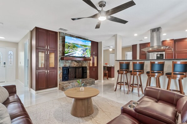 A modern living room with a fireplace, a television, and a bar area.