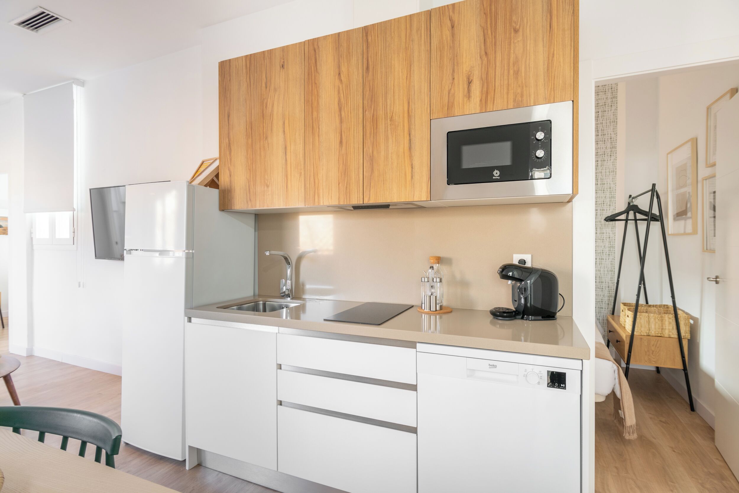 A modern kitchen with white cabinetry, a stainless steel microwave, and a coffee maker.