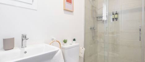Ein modernes Badezimmer mit Waschbecken, Toilette und Duschkabine aus Glas.