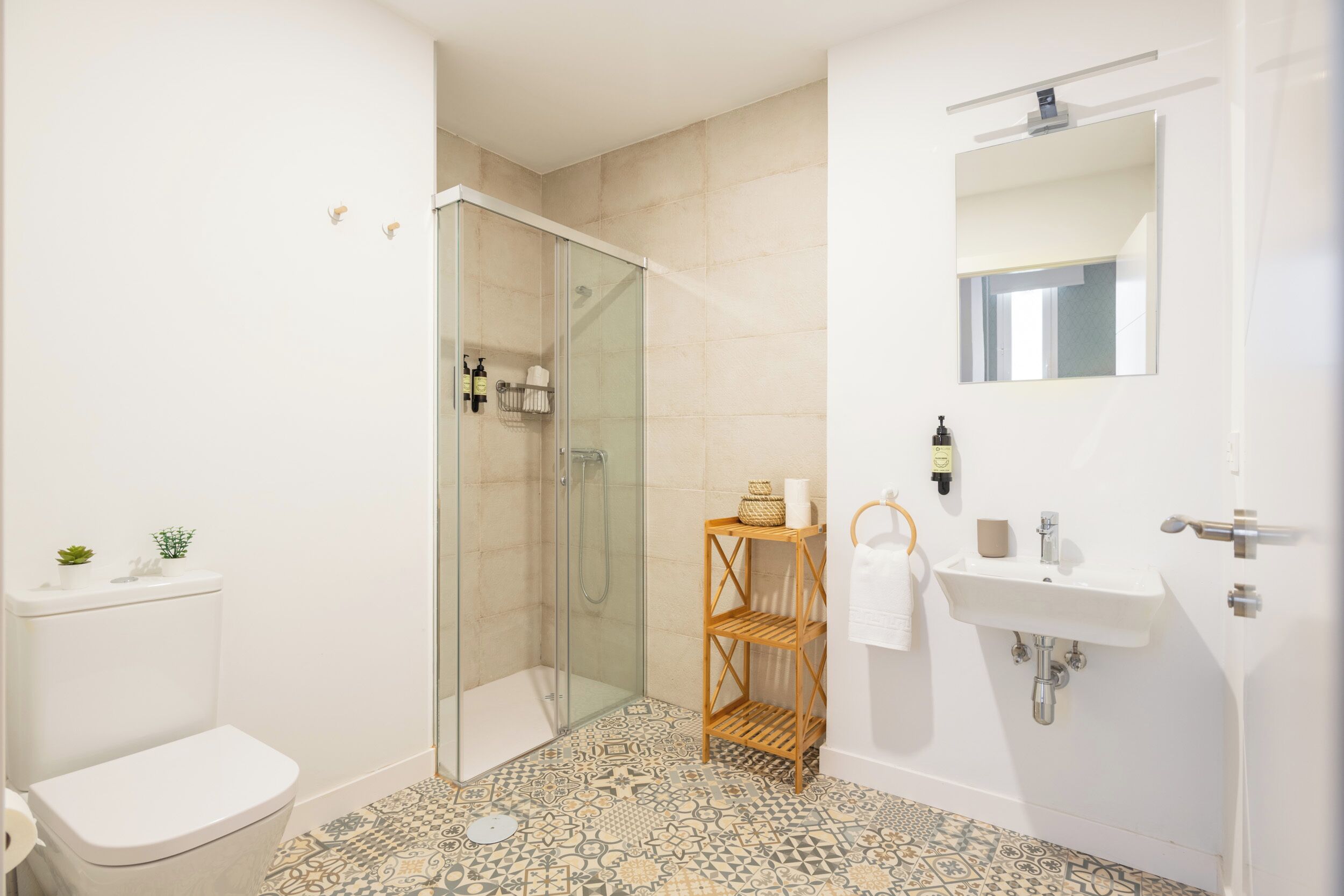Une salle de bain avec une douche à parois de verre, un lavabo blanc et un miroir au-dessus.