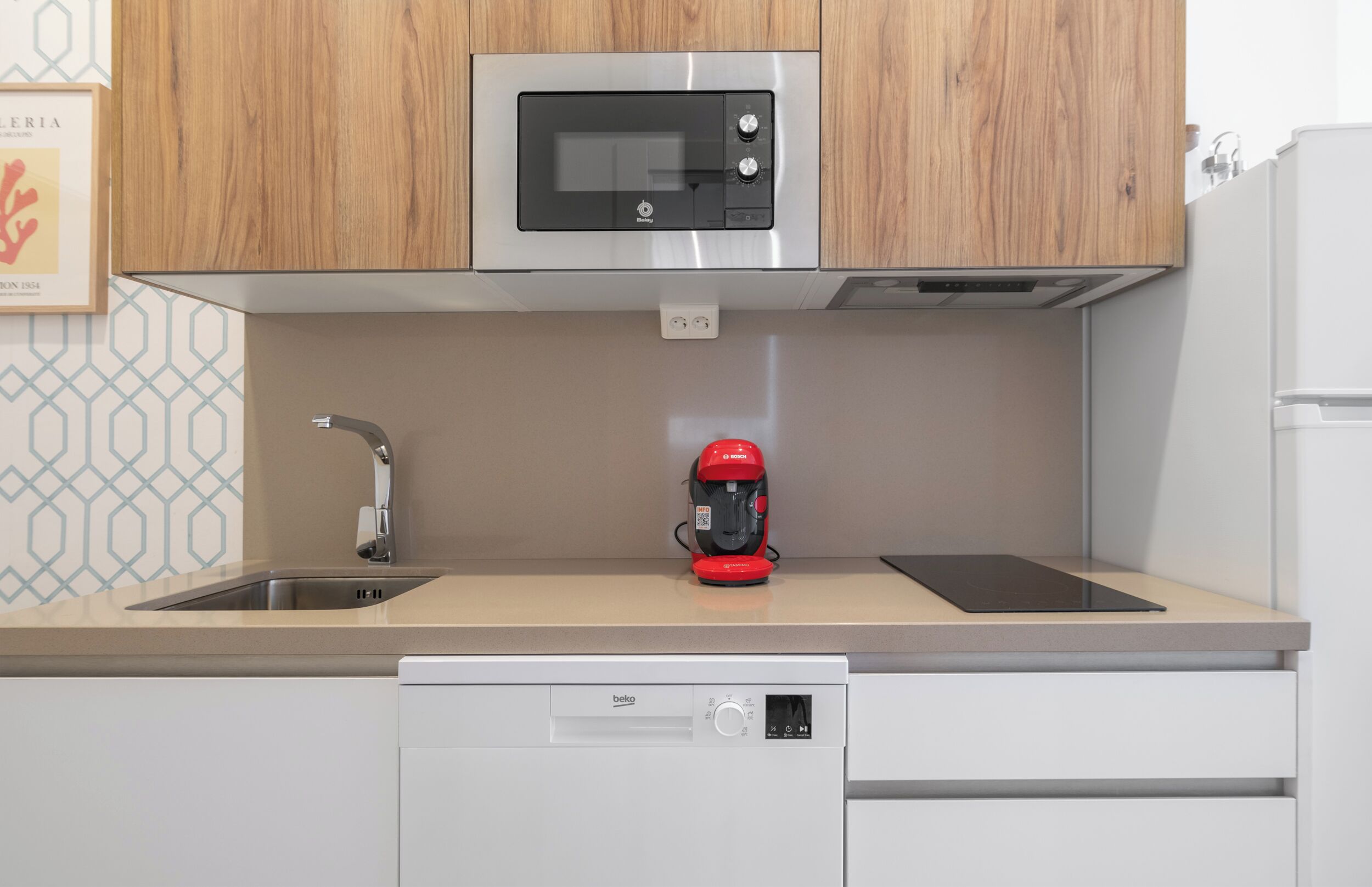 A kitchen with a microwave, coffee maker, dishwasher, and a sink.