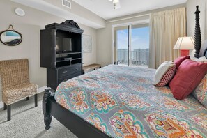 A hotel room with a large bed, a television, a chair, and a view of the city.