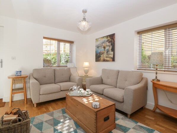 A cozy living room with two sofas, a wooden coffee table, and a chandelier.