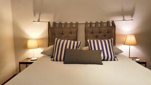 A double bed with striped pillows, a tufted headboard, and bedside lamps. - In Florence, in the heart of dowtown (Firenze)