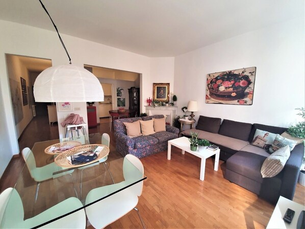 A modern living room with a sofa, a coffee table, and a dining area with chairs and a table.
