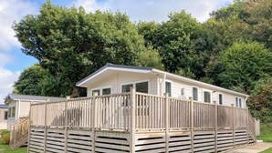 Une maison mobile dotée d’une terrasse en bois et d’un porche couvert.