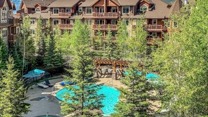Ein Resort mit mehreren Gebäuden, einem zentralen Poolbereich und umliegenden Bäumen.
