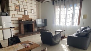 A living room with a fireplace, a television, a sofa, and a dining area with a map.