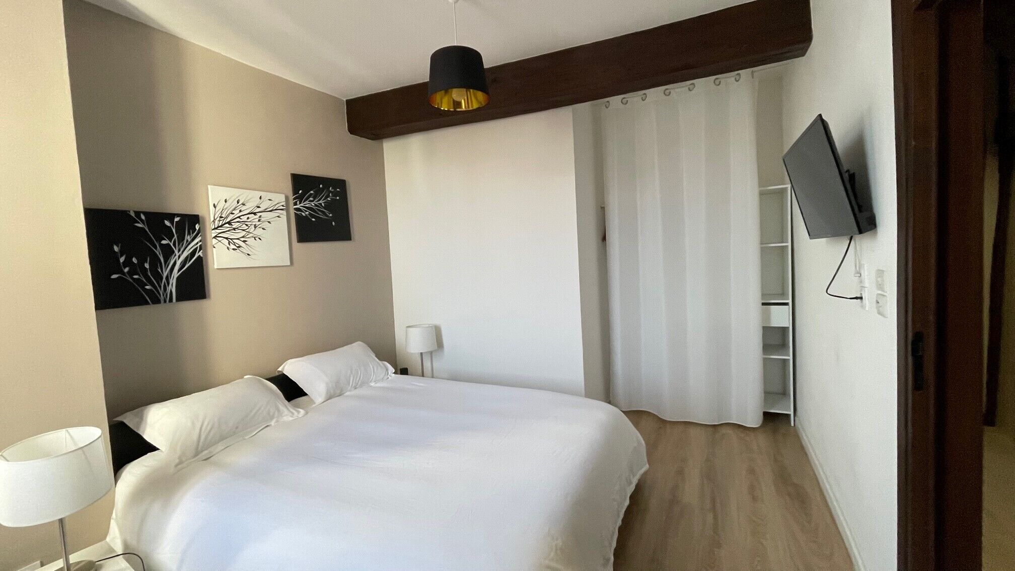 Une chambre d’hôtel avec un grand lit, un téléviseur à écran plat fixé au mur et des œuvres d’art accrochées aux murs.