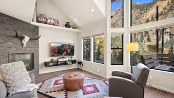 A modern living room with a fireplace, large windows, and a mountain view.