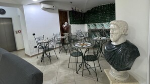 A dining area with round tables and chairs, a bust sculpture, and a clock on the wall. - Hotel Vistamare (Pozzuoli)