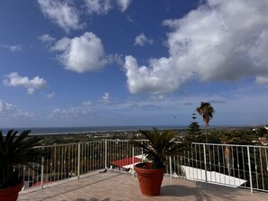 Un balcon offrant une vue sur la mer et sur les toits d’une ville lointaine.