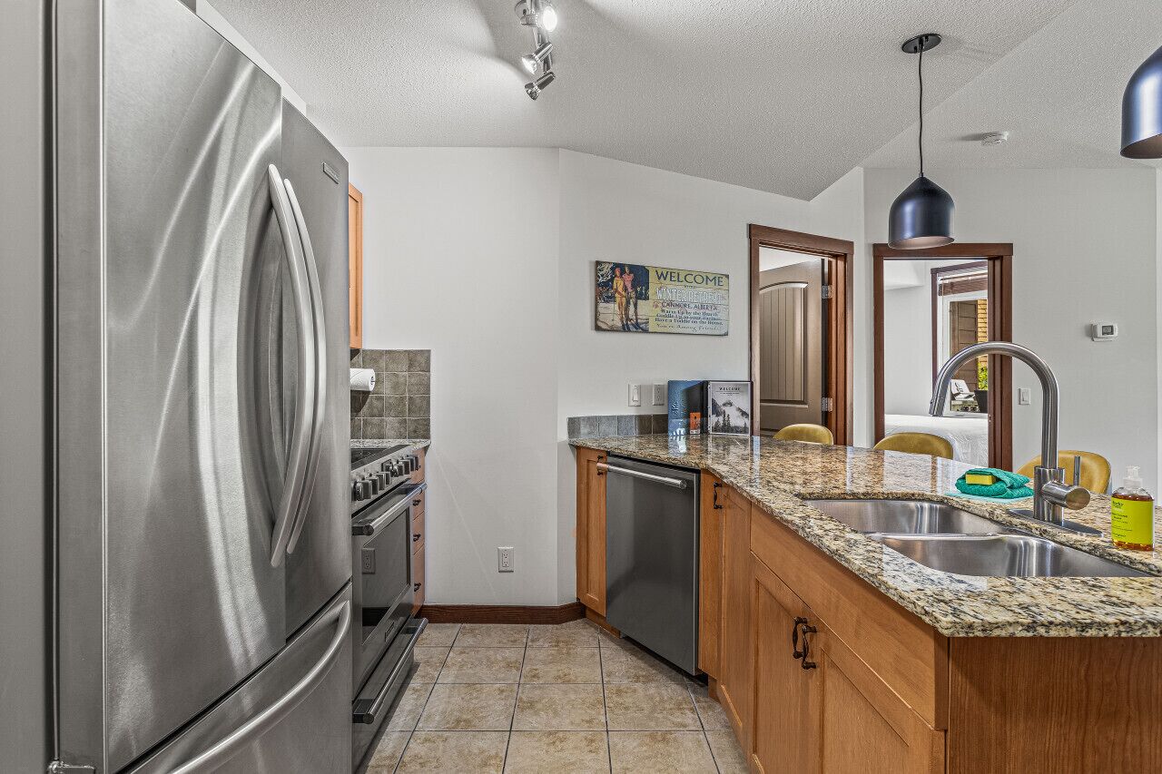 A modern kitchen with stainless steel appliances, granite countertops, and wooden cabinets.