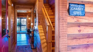 Un intérieur en bois avec un escalier, un panneau d’accueil et un coin repas comprenant une table et des chaises.