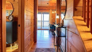 Un couloir intérieur en bois, avec un bureau, des chaises et une horloge.