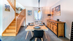 A dining area with a wooden table set for six, a staircase, and a wooden cabinet with drawers.