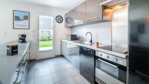 A modern kitchen with stainless steel appliances, a built-in dishwasher, and a coffee station.