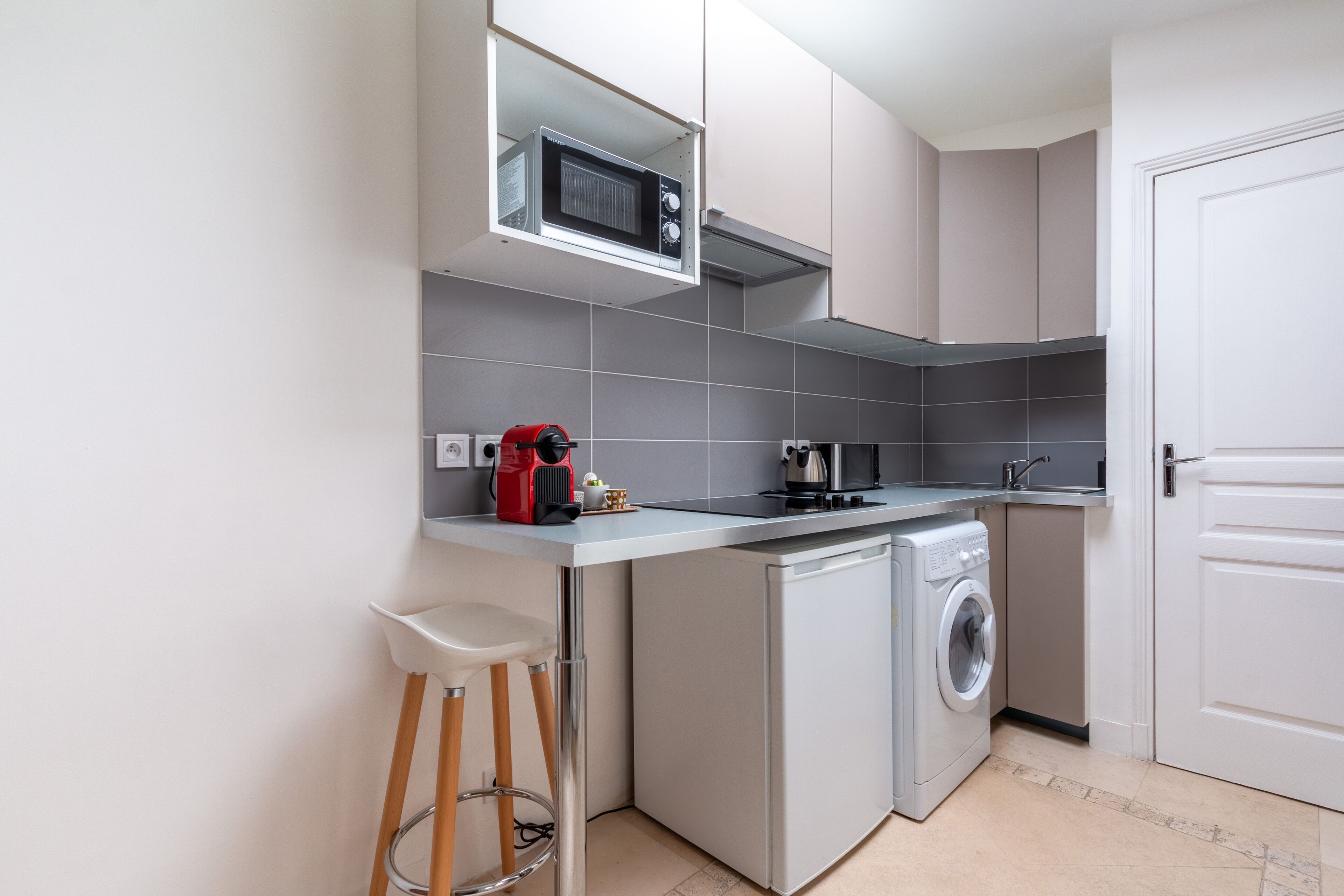Una cocina compacta con microondas, cafetera y lavadora.