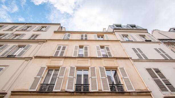 A multi-story building with evenly spaced windows and shutters.