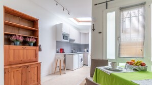 A compact kitchen with a microwave, washing machine, and a dining area with a table set for two.