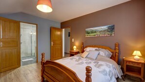 Ein Schlafzimmer mit einem hölzernen Bett, zwei Nachttischen mit Lampen, einer Duschkabine aus Glas und einem Gemälde an der Wand.