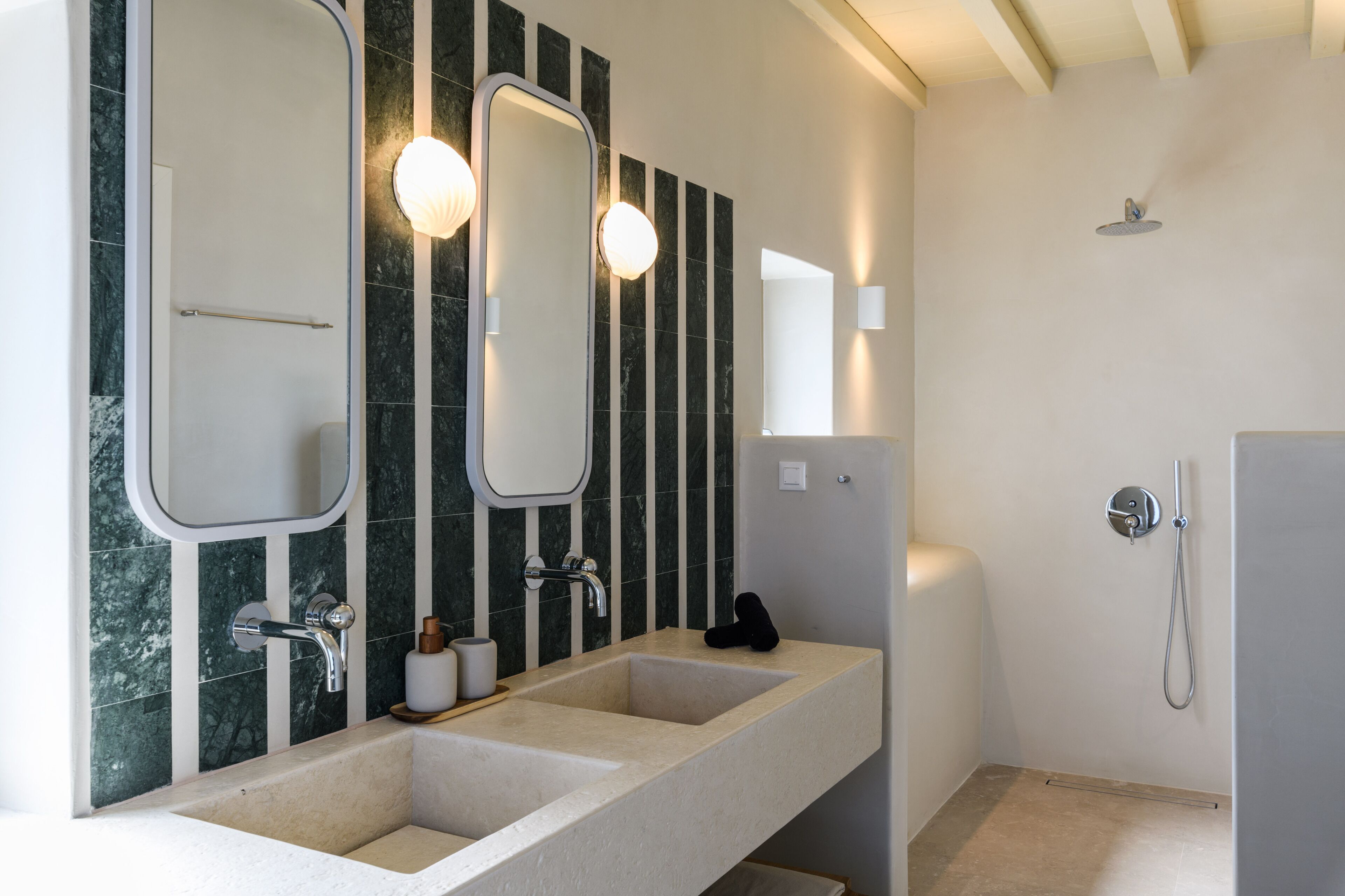 A modern bathroom with two sinks, a large mirror, and a shower.