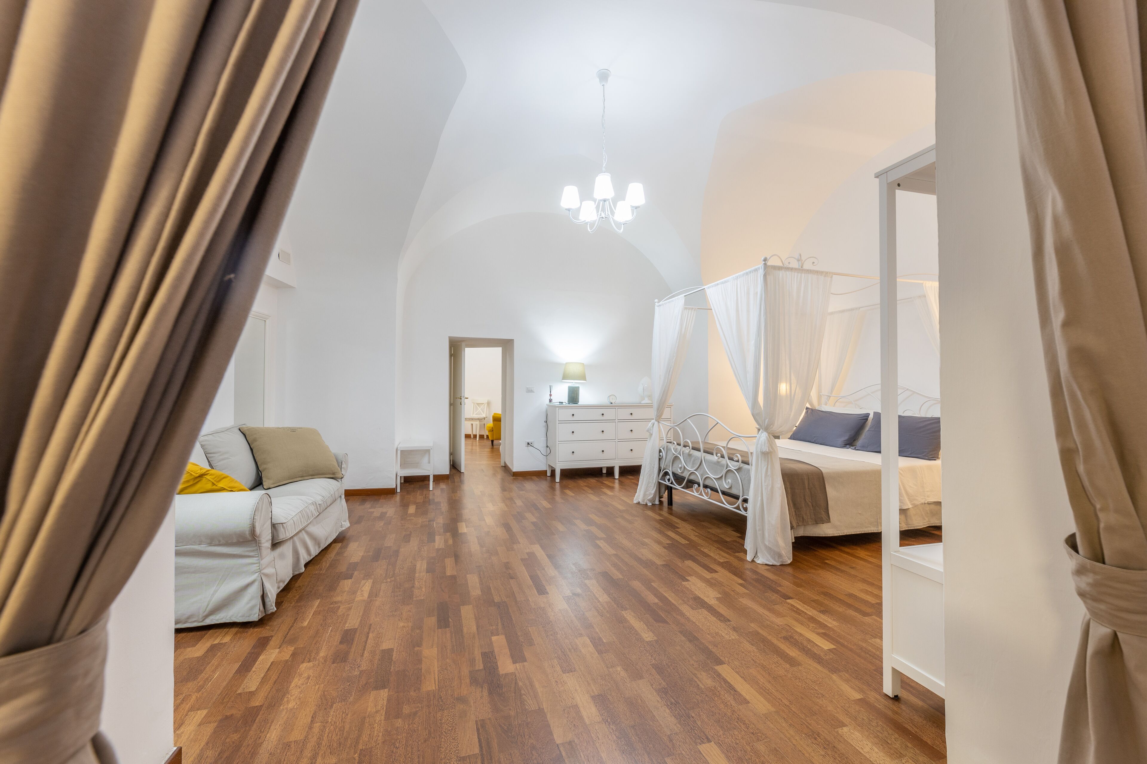 Ein Schlafzimmer mit Holzboden, einem Himmelbett, einem Nachttisch und einer Kommode.
