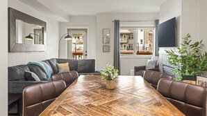 En moderne stue med et spisebord med fiskebensmønster, lædersofaer og et stort spejl.