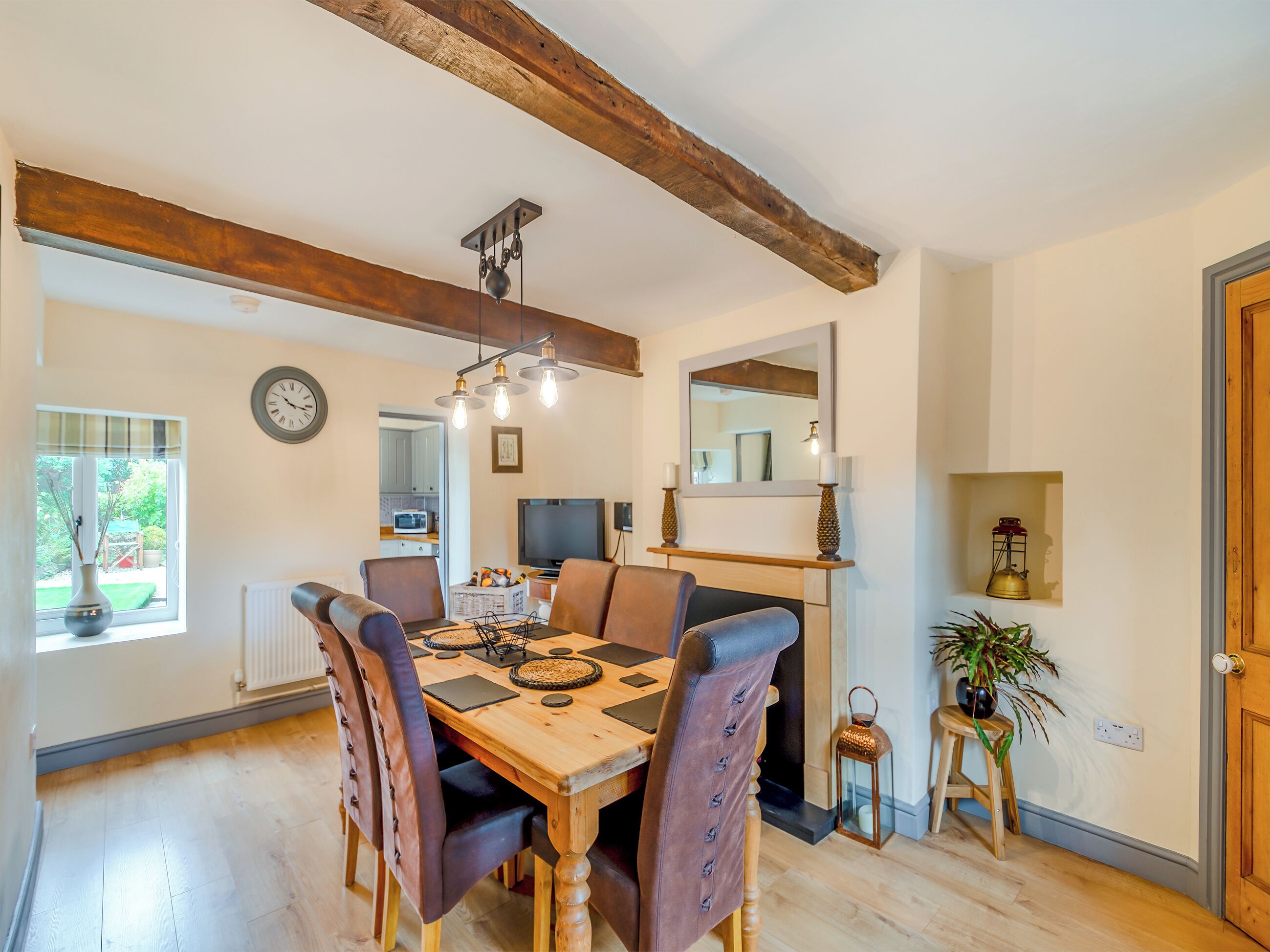 Un espace repas comprenant une table en bois, des chaises et un luminaire suspendu.