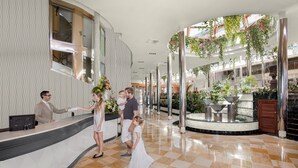 A hotel lobby with a checkered floor, a reception desk, and a large indoor garden with hanging plants. - Ona Palmira Paradise (Calvia)