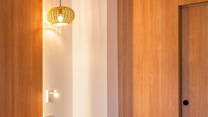 A bedroom with a bed, two pillows, a wall-mounted light, and a wooden door. - Ona Palmira Paradise (Calvia)