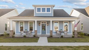 Une maison à deux étages avec un porche à l’avant, un petit hall d’entrée et un garage.