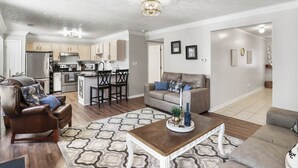 A spacious living room with a brown leather sofa, a wooden coffee table, and a patterned rug. - Spacious King Suite w/ Game Room, Fire Pit & Patio (Lexington)