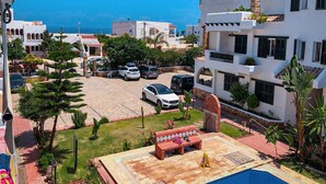 Zona residencial con piscina, coches aparcados y vista despejada al mar.