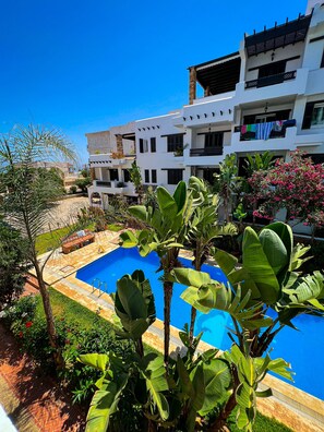 A modern building with balconies, a swimming pool, and lush greenery. - Visit Oued Laou: Jawhara (Oued Laou)