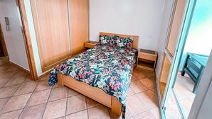 Un dormitorio con cama, armario de madera, mesita de noche y lámpara colgante.