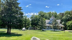 A large house with a well-maintained lawn and trees in the background.