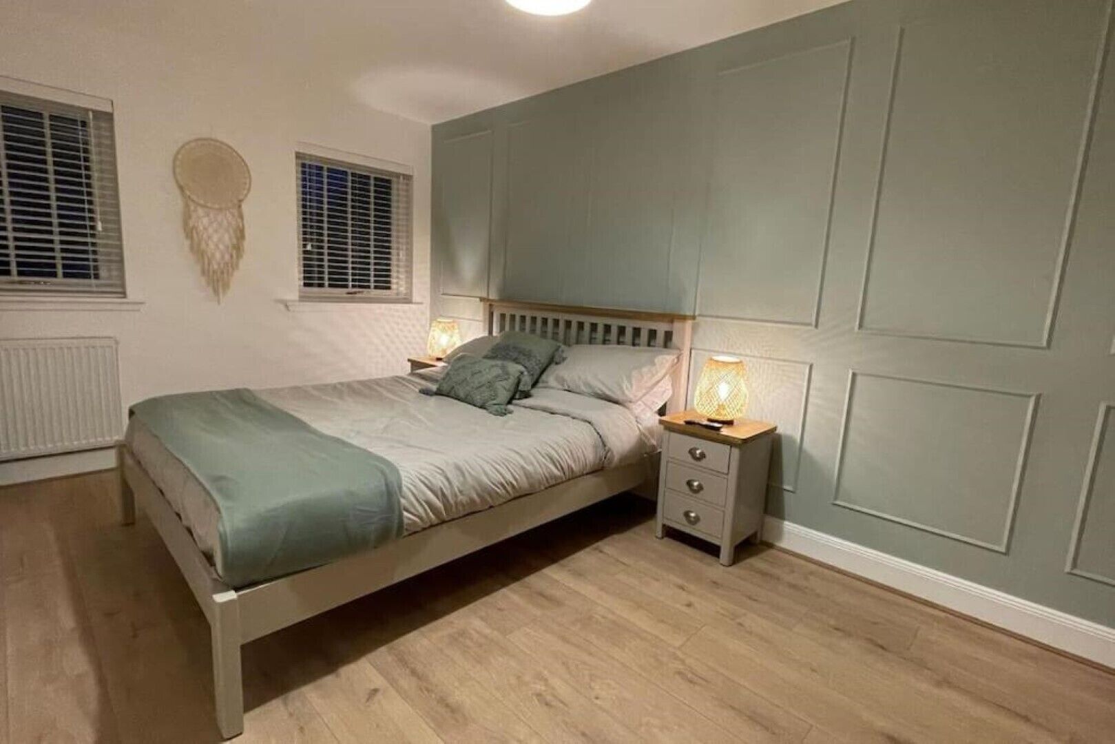 A bedroom with a bed, bedside tables, and a wall-mounted lamp.