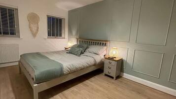 A bedroom with a bed, bedside tables, and a wall-mounted lamp.