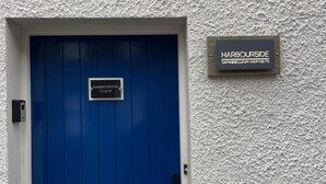 A blue door with a sign reading "Harbourside C.I.A.N." and another sign above it stating "Harbourside CATHESS LUXURY APARTMENTS." - Harbourside, Luxury Two Bedroom Townhouse with Bike store – Sleeps 6 (Wick)