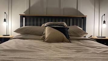 Ein Bett mit Holz-Kopfteil, zwei Nachttischlampen und einer Decke.