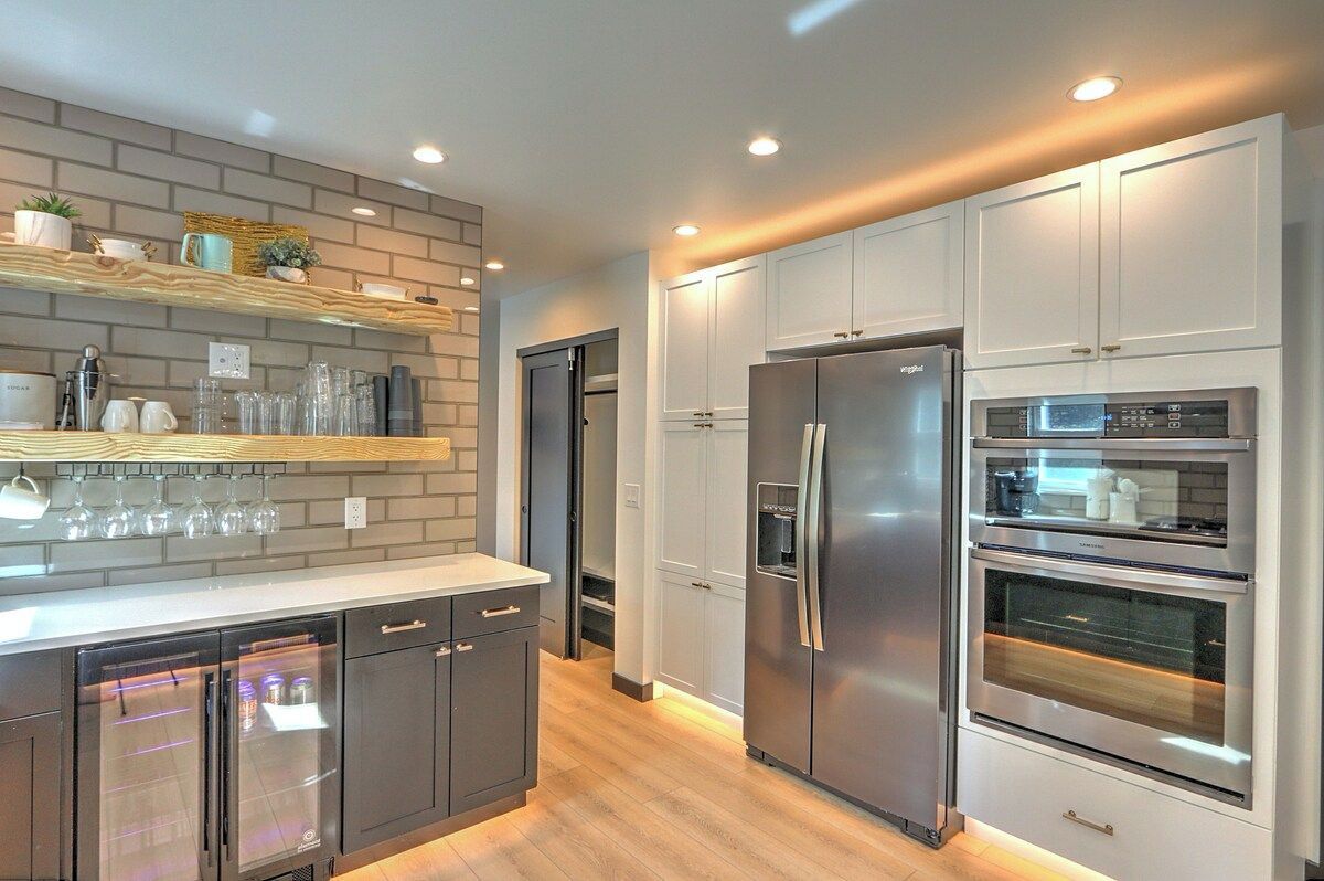 A modern kitchen with built-in appliances, a wooden countertop, and a brick backsplash.