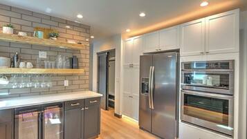 A modern kitchen with built-in appliances, a wooden countertop, and a brick backsplash.