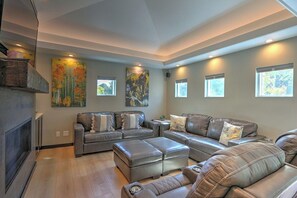 A modern living room with leather sofas, a fireplace, and artwork on the walls.