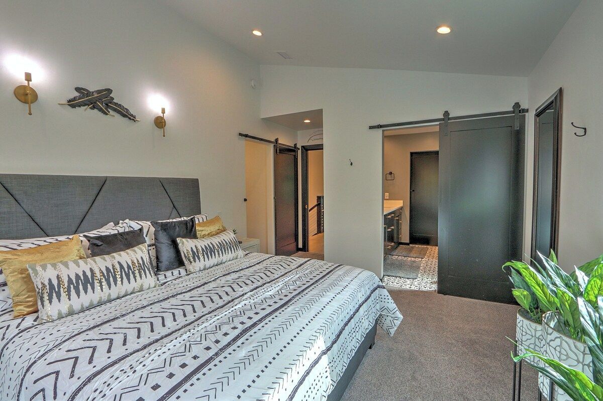 A modern bedroom with a large bed, a headboard, and a sliding door leading to a bathroom.