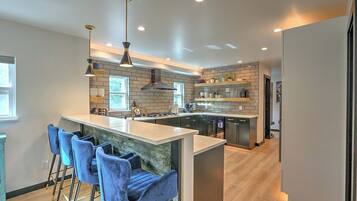 A modern kitchen with a central island, bar stools, and pendant lighting.