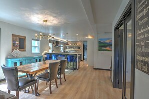 A modern kitchen with a central island, pendant lighting, and a dining area with a wooden table and chairs.