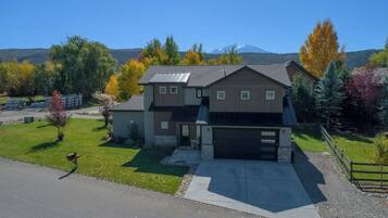A two-story house with a garage, surrounded by a well-maintained lawn and trees with autumn foliage.