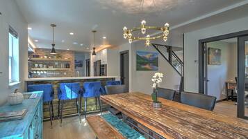 A modern kitchen with a bar area, a dining table with chairs, and a chandelier.